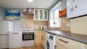 A compact kitchen with a dishwasher, oven, and washing machine. - Likely Sunset (St Austell)