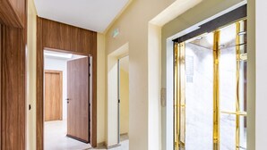 Ein Korridor mit Holztüren, einem Marmorboden und einer Glastür mit goldener Rahmung.