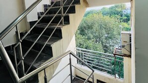 A staircase with metal railings leading to an outdoor area with greenery. - Roomshala NP International (New Delhi)