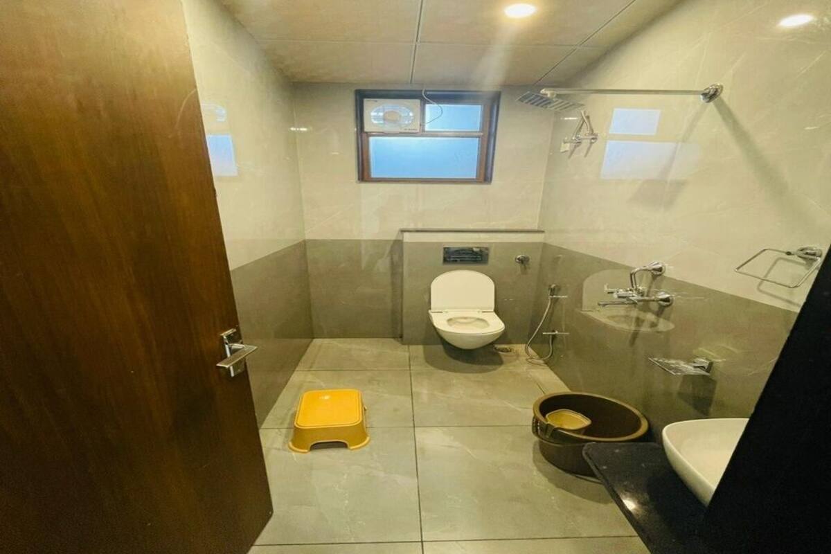 Un baño con inodoro, ducha, lavamanos y un ventanal pequeño.
