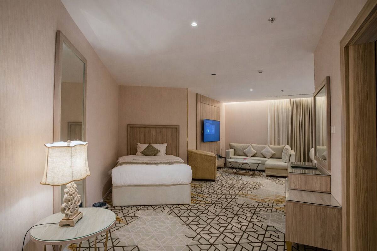 Una habitación de hotel con una cama, un sofá, un televisor y un espejo.