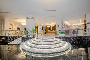 Een hotellobby met marmeren treden, een receptiebalie en een trap.