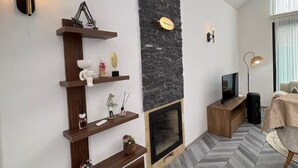 Una sala de estar moderna con chimenea, estanterías de madera, televisor y comedor.