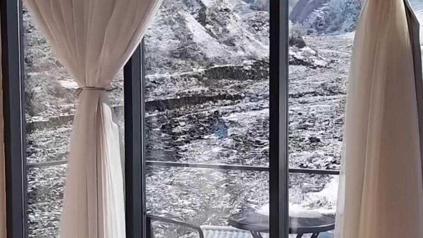 Un dormitorio con una cama grande, una mesita de cristal y cortinas.