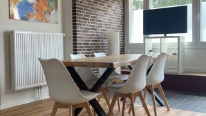 A modern dining area with a brick accent wall, a white radiator, and a large window. - Urban & close to nature at Alter Bahnhof near Hamburg Bright apartment with 3 bedrooms (Trittau)