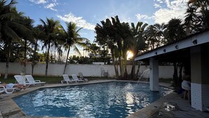 A swimming pool with lounge chairs, palm trees, and a white building. - Luxury Mansion in Barra / Sleeps 50 + Events, Gated Community + 24-hour Security (Rio de Janeiro)