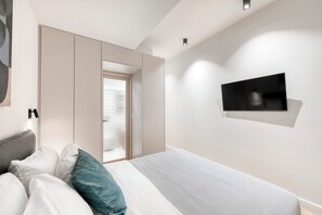 A modern bedroom with a bed, a TV mounted on the wall, and a sliding door closet. - Spacious Modern Apartment- Heart of Glyfada Center (Glifada)