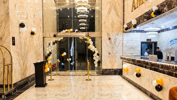 A marble lobby with a reception desk, a chandelier, and a wall with the name 'AMCO'. - AMCO Serviced Apartments (Jeddah)