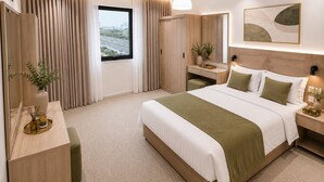 A modern hotel room with a large bed, a vanity, a desk, and a view of the cityscape through the window. - AMCO Serviced Apartments (Jeddah)