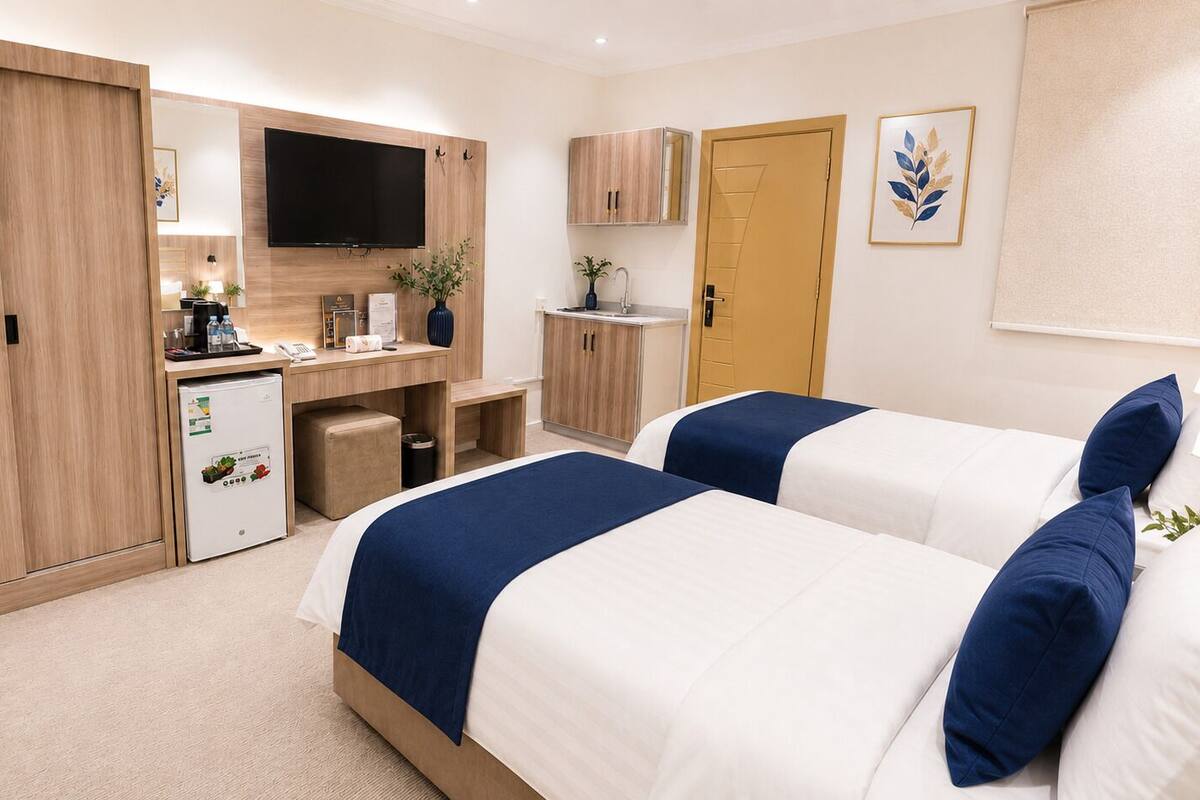 Habitación de hotel con dos camas, un escritorio, televisión de pantalla plana, minibar y armario.