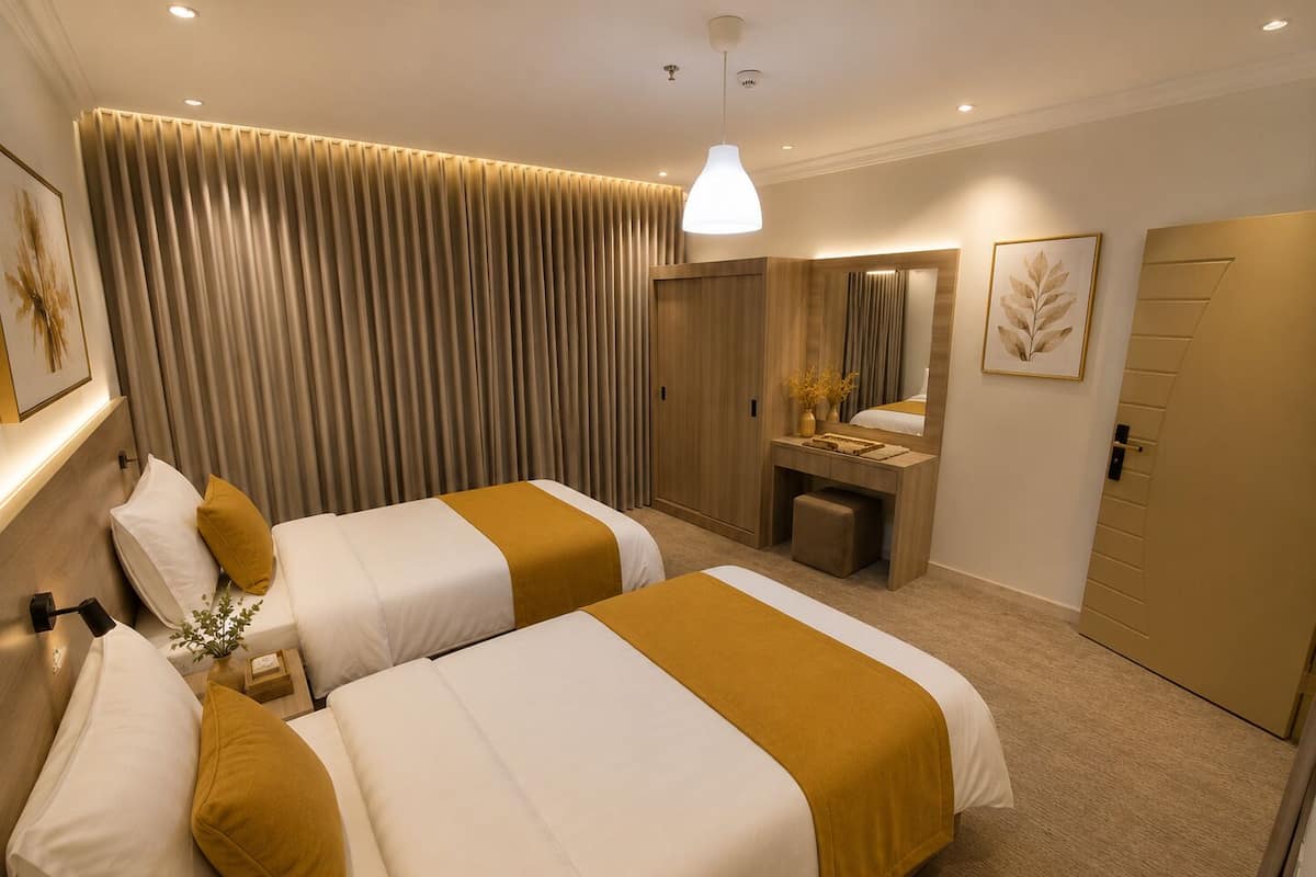 Habitación de hotel con dos camas, un escritorio, un espejo y un armario.