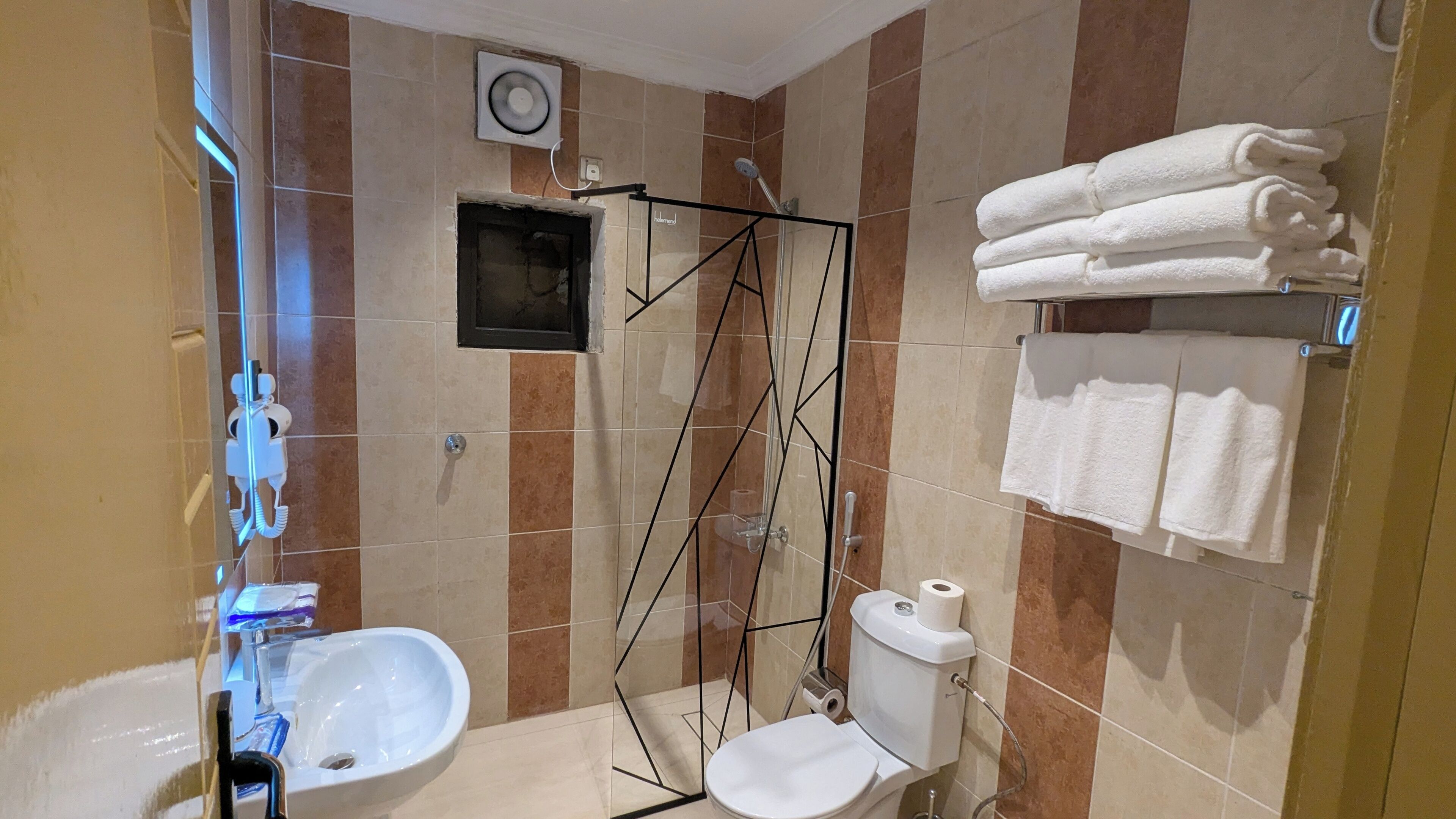Un baño con bidé, inodoro y cabina de ducha de vidrio.
