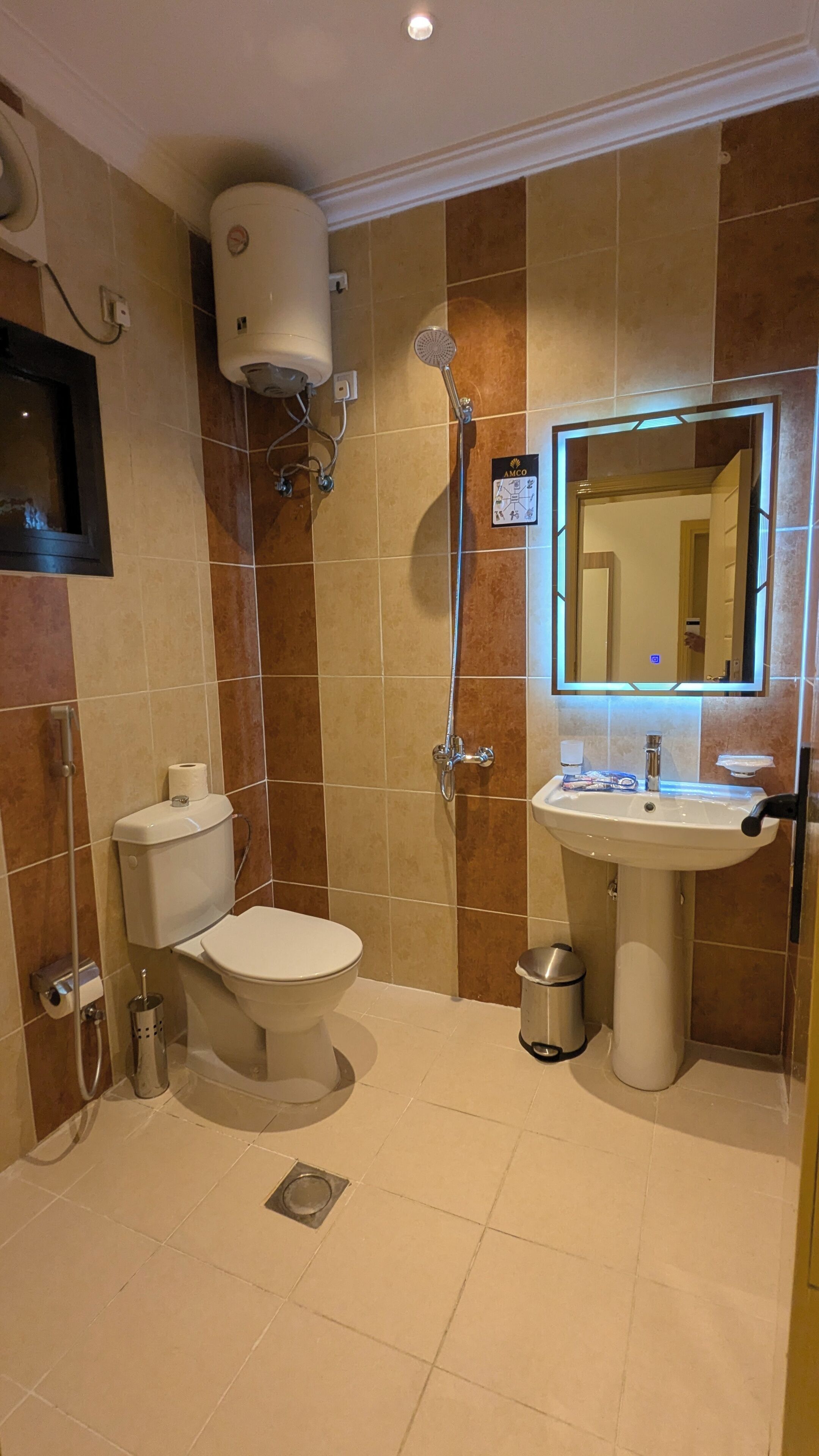 A bathroom with a toilet, shower, sink, and mirror.