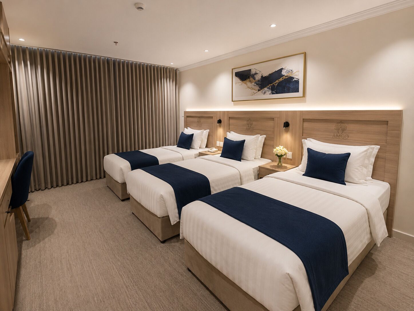 Habitación de hotel con tres camas, un escritorio y un ventanal con cortinas.