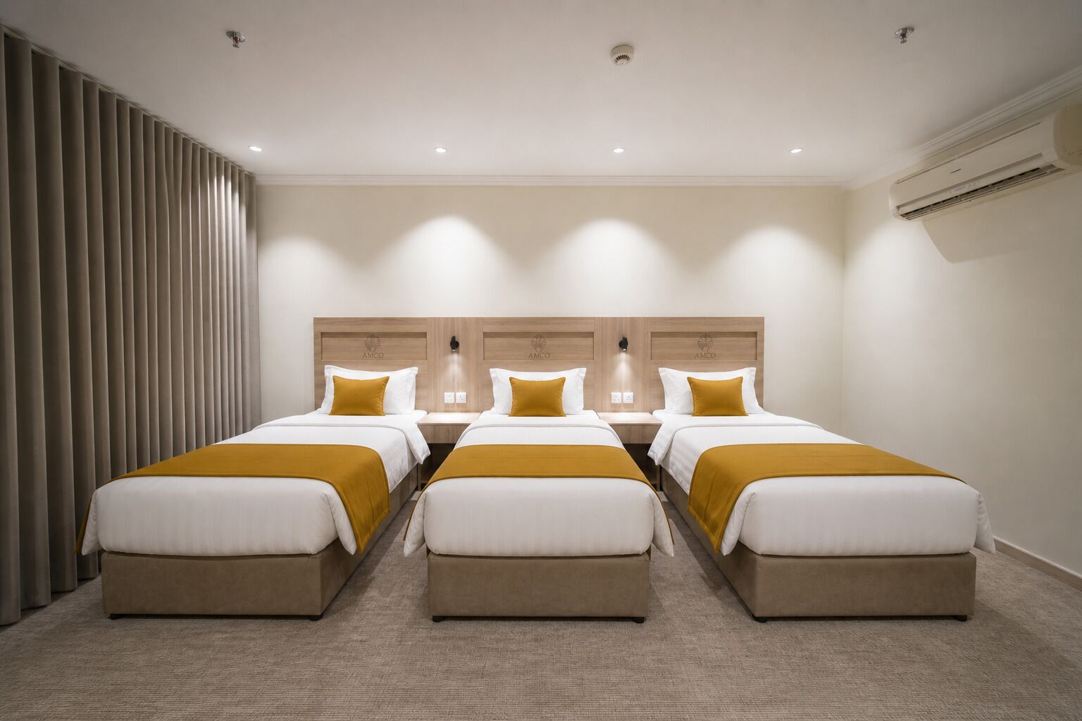 Een hotelkamer met vier bedden, een groot raam met gordijnen, een airconditioning en een wandlamp.