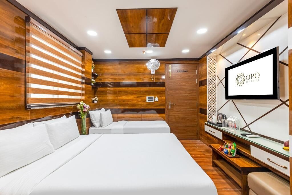 Una habitación de hotel con una cama, un televisor, una pared de madera y un armario de madera.
