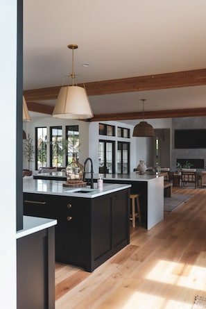 A modern kitchen with a large island, wooden beams, and pendant lighting. - Group destination! 19 beds. Basketball/pickleball court/hottub/sauna/coldplunge. (Monroe)