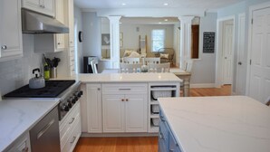 Una cocina moderna con armarios blancos, extractor de acero inoxidable y una isla central.
