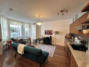 Ein großzügiger Wohnbereich mit Sofa, Esstisch und Küchenzeile mit Holzausbau und Herd.