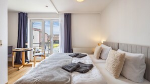 Een hotelkamer met een bed, een tafeltje, een stoel, een bank en uitzicht op buiten.