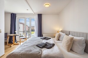 Camera d'albergo con un letto, un tavolino, una sedia, un divano e vista sull'esterno.