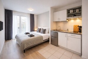 A modern hotel room with a bed, bedside table, and a kitchenette. - Apartment 'Double Studio' with Wi-Fi (Lübeck)