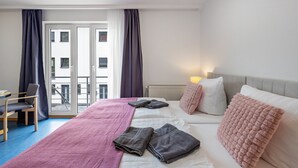 A hotel room with a bed, a desk, a chair, and a view of the outside. - Apartment 'Double Studio' with Wi-Fi (Lübeck)