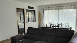 En stue med en hjørnesofa, et træbord og et spiseområde med stole og bord.