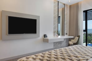 A modern bedroom with a large TV, a bedside table, a chair, and a view of the outdoors. - The Encore Hotel Nakuru (Nakuru)