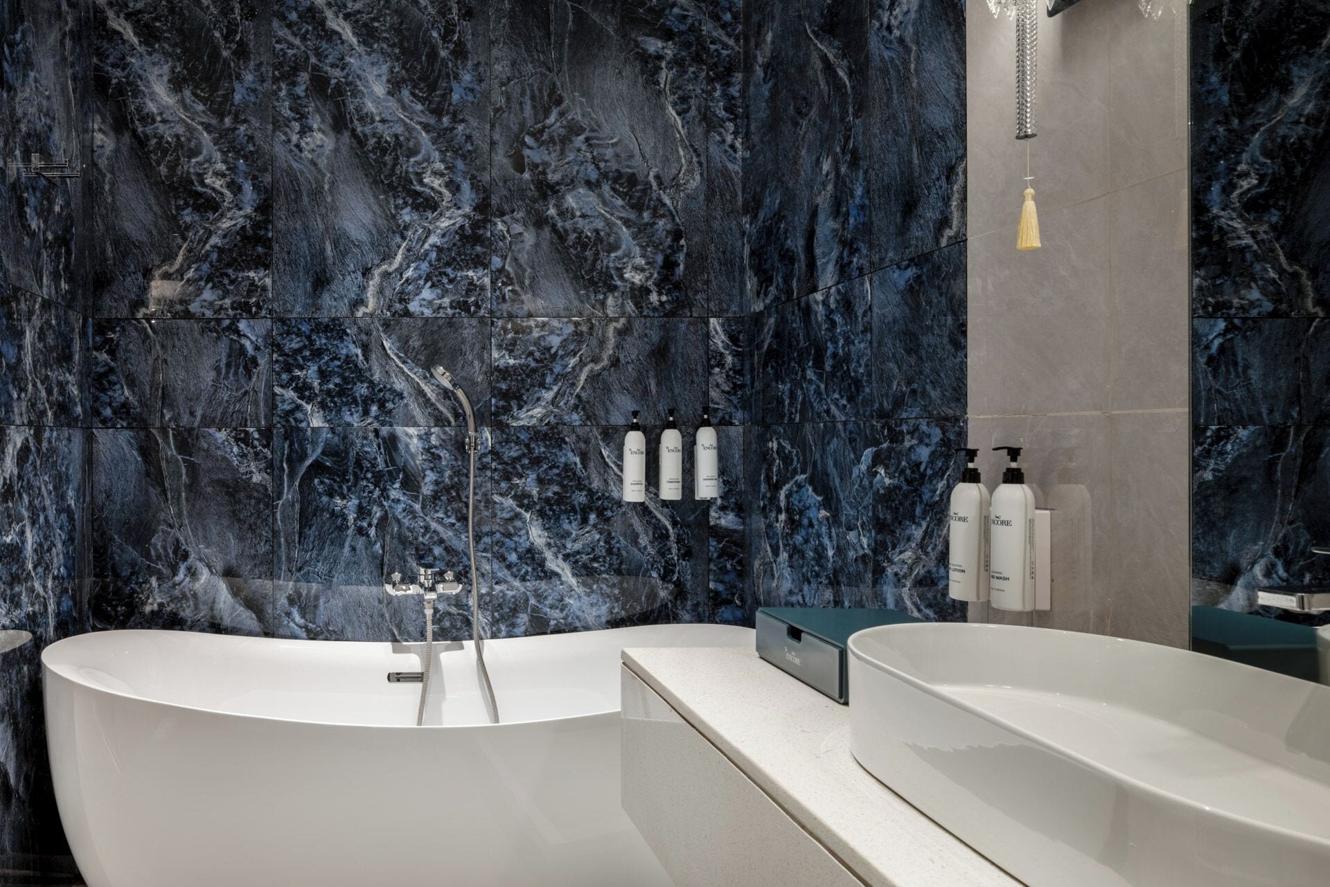 Un baño moderno con una bañera independiente, un tocador con espejo y una pared de mármol.
