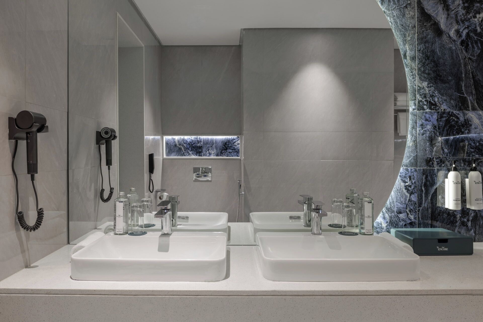 A modern bathroom with two sinks, a hairdryer, and a large mirror.