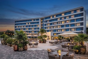 Un hotel con varios pisos, terraza al aire libre y plantas en macetas.