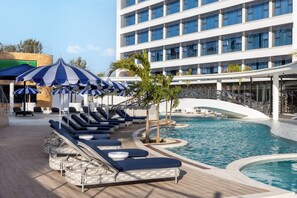 A poolside area with lounge chairs and umbrellas, a pool, and a modern building in the background. - The Encore Hotel Nakuru (Nakuru)