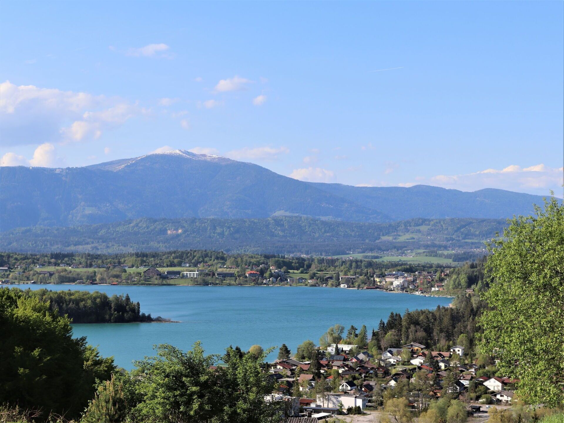 Un lago rodeado de montañas y un pequeño pueblo con casas.