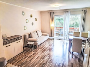 A modern living room with a sofa, a small table, and a dining area with chairs.