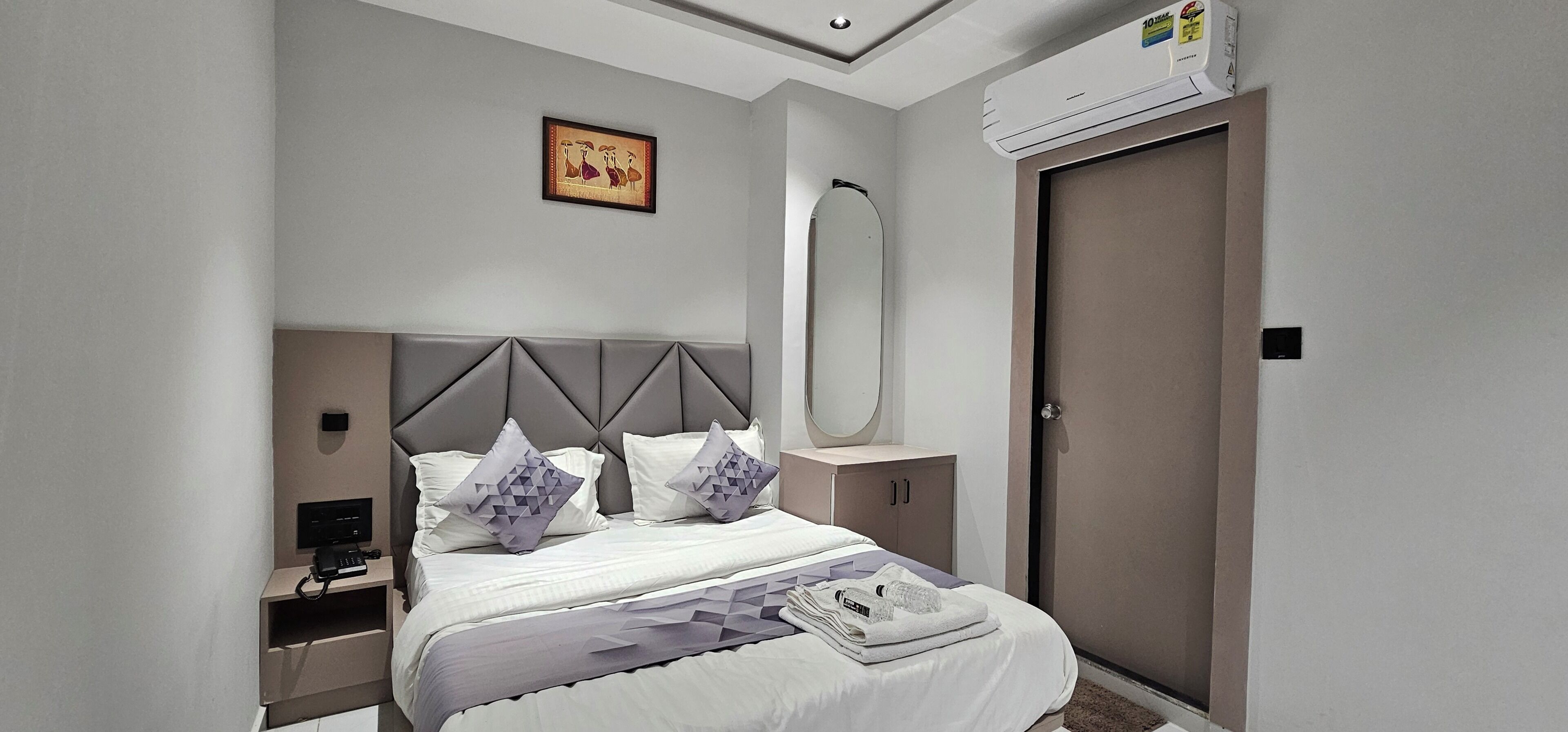 Un dormitorio con cama, mesita de noche, armario y aire acondicionado.