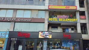 A multi-story building with various businesses including a restaurant, a hotel, and a clothing store. - Hotel Bellemount (Ahmedabad)
