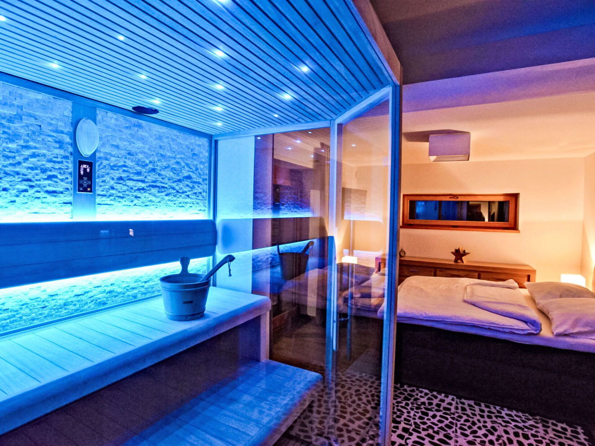 Una habitación moderna con separador de vidrio, una cama, una mesita y ventana con vista a la playa.