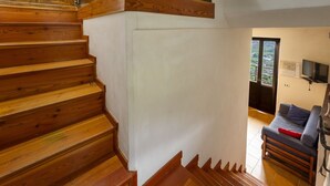 Una escalera de madera que conduce a una sala de estar con un sofá y una televisión.