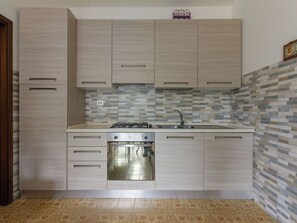 Una cocina con alacenas de madera clara, estufa de acero inoxidable y salpicadero de azulejos.