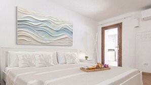 Ein Schlafzimmer mit einem großen Bett, einem Nachttisch mit Lampe und einem an der Wand hängenden Kunstwerk.