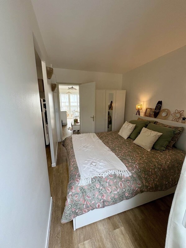 Quarto com cama, guarda-roupa, mesa de cabeceira e luminária.