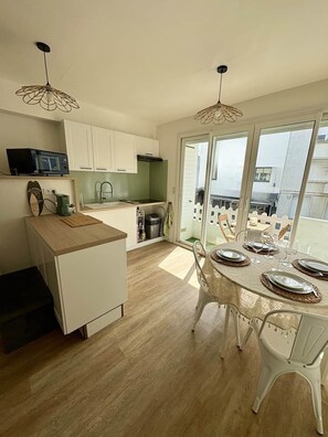 Una cocina moderna con armarios blancos, encimera de madera y un comedor con mesa para cuatro.