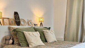 Ein Schlafzimmer mit Bett, Kissen, einem Teddybären, Wanddekoration und einer Lampe.