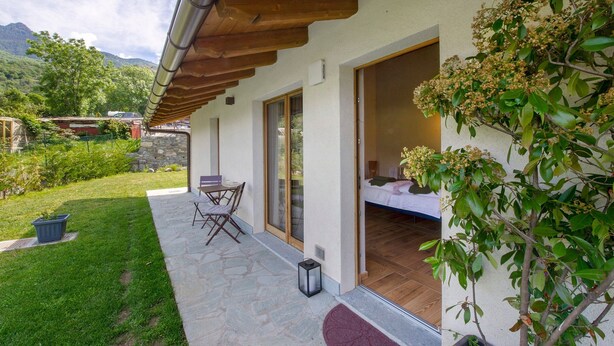 A modern house with a patio, a dining area, and a bedroom with a view of the mountains.