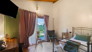 Un dormitorio con cama, una silla, un escritorio y una ventana con cortinas.