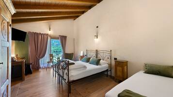 Un dormitorio con una cama de madera, un escritorio con silla, un armario pequeño y vistas al exterior con vegetación.