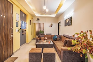 A modern living room with a sofa, coffee table, and a television. - Santa Fe 1BHK CityView by Homeyhuts (Dehradun)