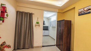 Un couloir avec une armoire en bois sombre, un rideau gris et une petite plante accrochée au mur.