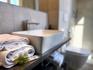Een badkamer met een wastafel, handdoeken en toiletartikelen.
